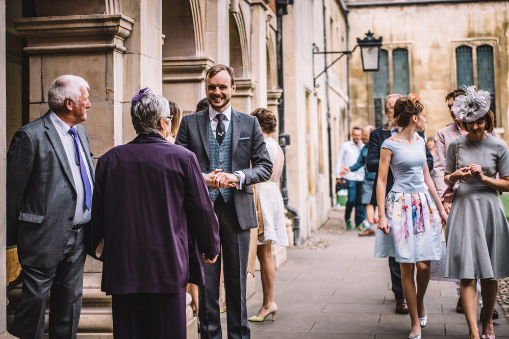 groom meeting guests at pembroke college wedding photography
