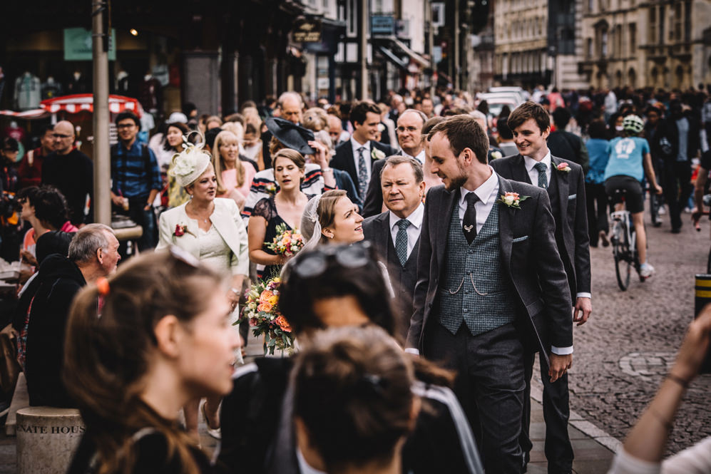 bride and groom walking through busy streets of cambridge